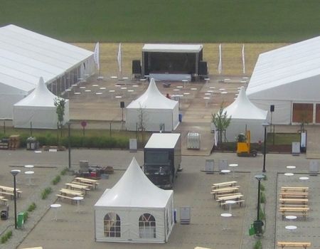 Außenansicht einer Zeltveranstaltung mit mehreren Zelten und Sitzbereichen.