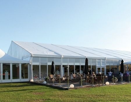 ußenansicht eines eleganten Festzeltes mit weißen Dächern und Glaswänden.
