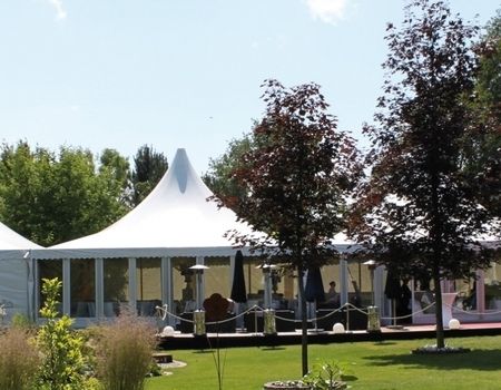 ußenansicht eines eleganten Festzeltes mit weißen Dächern und Glaswänden.