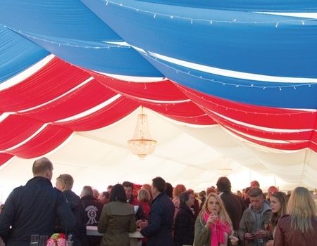 Innenansicht eines Festzeltes mit bunten Stoffen und vielen Menschen.