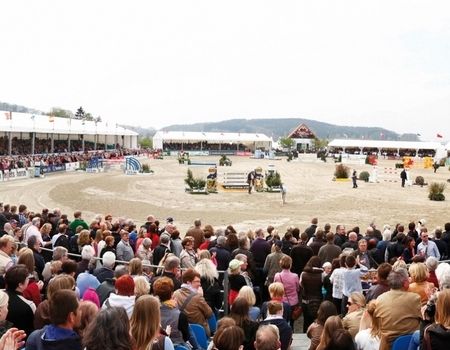 Zuschauer beim Reitturnier mit vielen Menschen und Zelten im Hintergrund.