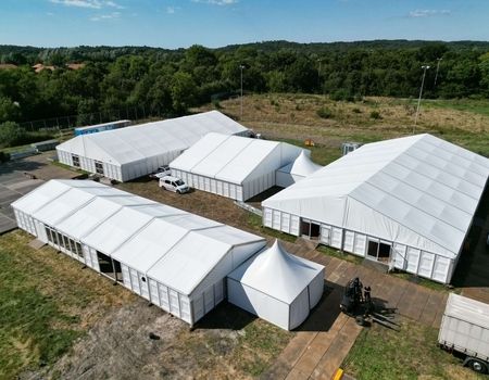 Luftaufnahme einer Zeltanlage mit mehreren weißen Zelten im Freien.
