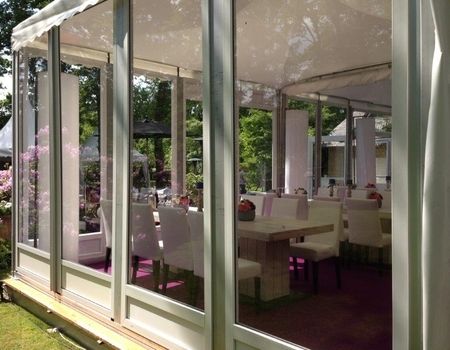 Innenansicht eines eleganten Glasgartens mit Tischen und Stühlen